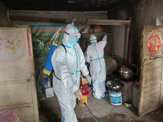  两名身穿防护服、戴着护镜、口罩的工作人员正在王思家的房屋消毒。&nbsp; 受访者供图