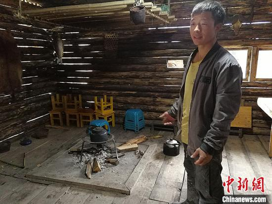 图为白忠平介绍自己设计的复原了独龙族火塘风貌的“酒店大堂”。 中新社记者 胡远航 摄