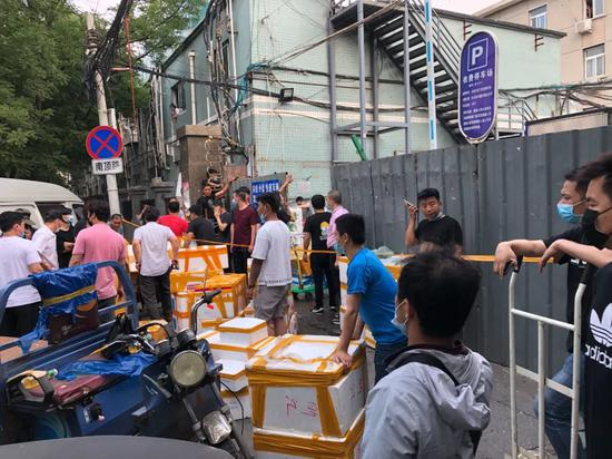 　　6月13日下午，北京大红门京深海鲜批发市场北门，市场的一些商户聚集在此，将产品从市场往外运走。摄影/本刊记者 张旭