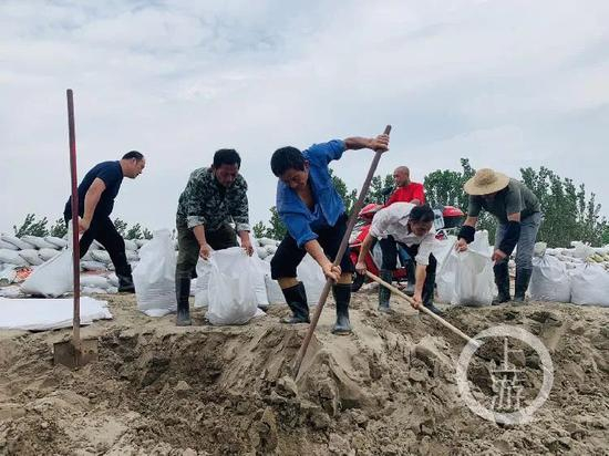  7月13日，江西九江市江洲镇，当地村民正在装沙袋堤坝修筑。/记者 时婷婷