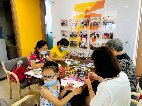 居民带着孙女一同来做社区志愿者，为邻里汇制作装饰画。 舒抒 摄于今年7月