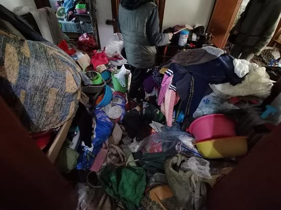 家中堆满了废品杂物，每次进出老人都要从这些杂物上爬进爬出。