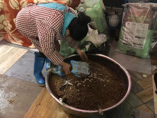 ▲工人把狗粮倒在直径近半米的大盆里，1300只狗一顿要吃七八盆。新京报记者&nbsp;王翀鹏程 摄