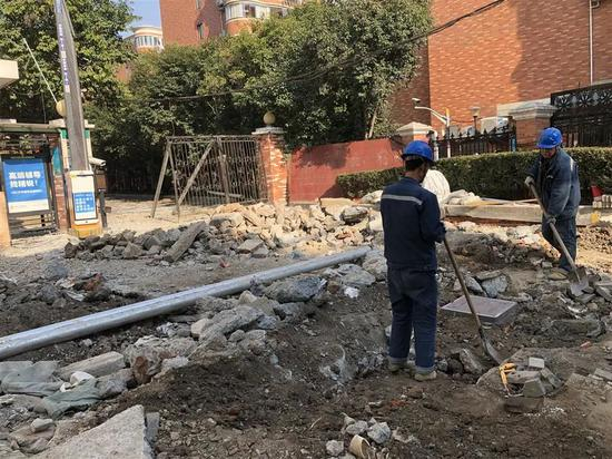 　　△天山路双流路路口，东北角绿康公寓门口，身穿蓝色制服的工人们正在往开挖处回填渣土。整条人行道都被挖得七零八落。