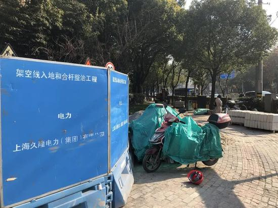 △仁恒河滨花园小区前人行道蓝色施工围挡上，喷有“架空线入地和合杆整治工程”字样。