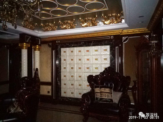 “暗黑客厅”的左侧（西北侧）墙壁及凌乱摆放的木雕真皮沙发。此客厅无自然光线进入，且客厅的正面为一块巨幅黑色带纹路的花岗石，更显得该公用客厅有一丝庄重、沉稳的氛围。但这一氛围，在金碧辉煌的屋顶、吊灯、墙壁、家具等富贵之气辉映下，体现出一种特殊的奢华。&nbsp; &nbsp; 《等深线》记者&nbsp;程维 摄