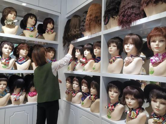 2021年3月11日，店员在舒庭去年新开的分店里帮忙梳理假发。&nbsp;