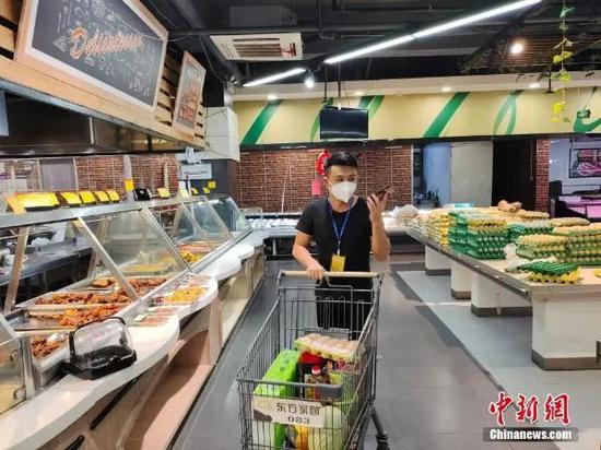  7月7日，云南瑞丽，一名工作人员在超市采购物资。当日，云南省瑞丽市因新冠肺炎疫情对主城区所有市民实行居家隔离管理。中新社记者 韩帅南 摄