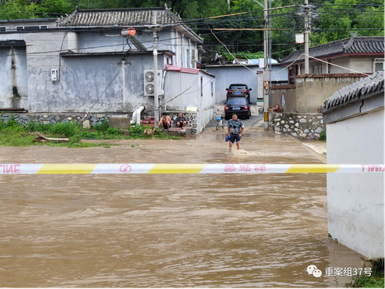 　　▲7月18日，受暴雨天气影响，北京门头沟区担礼村进村的漫水桥被淹。村里安排专人在两侧桥头值守，提醒趟水过桥的村民注意安全。新京报记者 慕宏举 摄