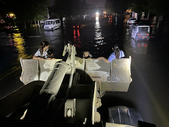 在积水严重的情况下，装载车成为最好的转移工具。夜色中，依稀可见水中等待转移的群众。