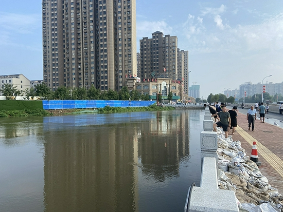 水位不断上涨的孟姜女河畔，救灾人员搬来了沙袋堵在河沿边。