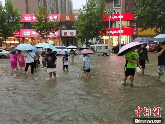 资料图：郑州7·20特大暴雨后，市民在街道上趟水而过。　王登峰 　摄