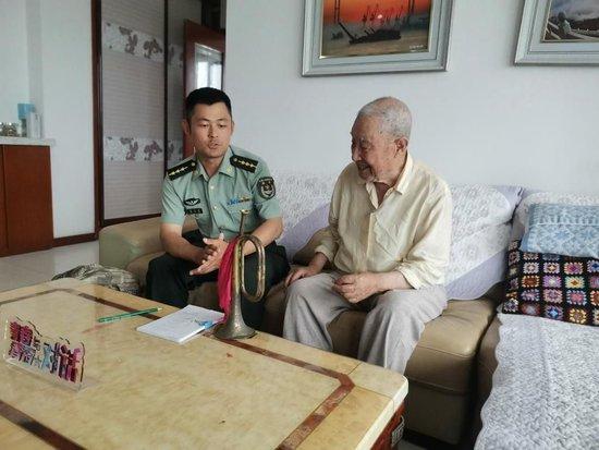 志愿军老战士孙凯丰（右）向“虎头连”现任连指导员陈天龙讲述战场经历。（丹东军分区供图）