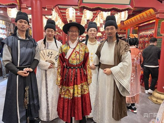  长安十二时辰主题街区内，游客和演员互动合影，中间着红装者为游客（总台中国之声记者管昕摄）