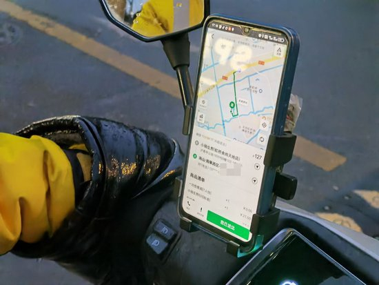 △美团骑手小王的送餐界面显示，在沪青平公路上，平台指引他逆行以达到“距离更短”。