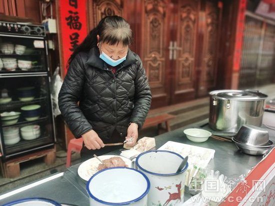 俞邦村“寻根追味”小吃街上，手打扁肉技艺传承人俞和传的妻子正在包扁肉。（中国经济网记者 武晓娟/摄）