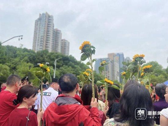 家长举着寓意“一举夺魁”的向日葵给孩子加油