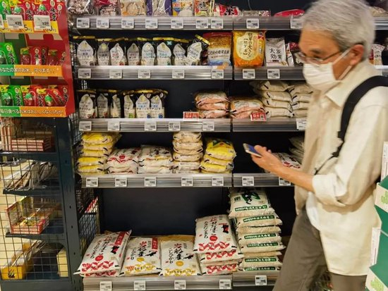 2024年7月26日，在日本东京一家连锁超市，一名男子经过摆放大米的货架。图：新华社