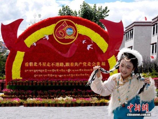 8月19日,随着西藏自治区成立60周年庆祝活动临近,拉萨氛围浓。图为游客在拉萨大昭寺广场上的大庆宣传标语前留念。中新社记者 李林 摄