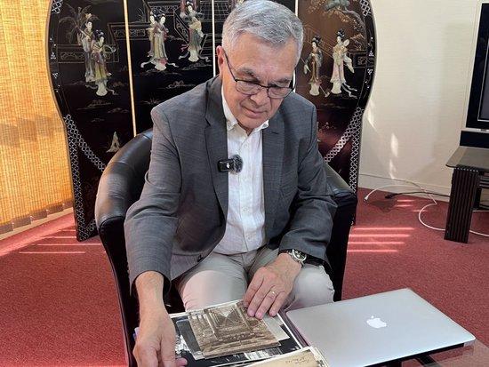 2025年6月23日,贝石涛在巴黎近郊接受记者采访时翻看与贝熙业医生相关的历史资料。新华社记者 孙鑫晶 摄