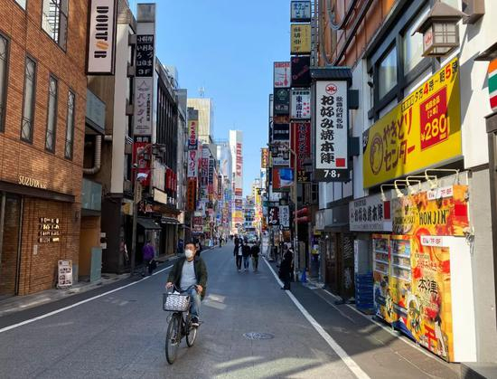 2020年4月2日，戴着口罩的行人从新宿东口歌舞伎町一番街前走过。