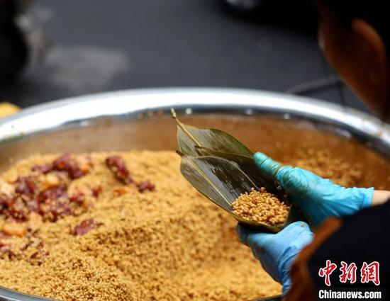 资料图：商家正在包粽子，手速快的“高手”十秒内就能包好一个。　吕杨 摄