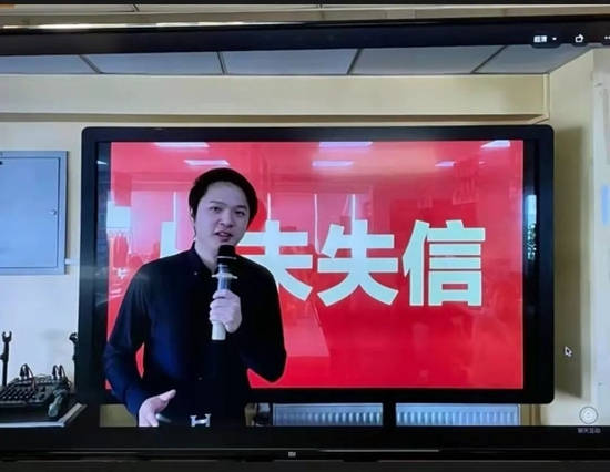  ·童哲在公司内部会议上讲话，背景写着“从未失信”。（受访者供图）