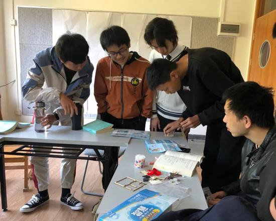  学生们打开科学实验手工材料包，准备组装实验