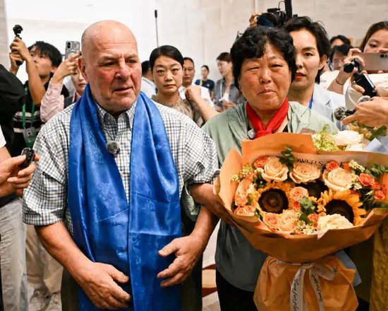 ·2026年8月23日，阔别26年的罗纳德·萨科尔斯基和殷玉珍在内蒙古鄂尔多斯机场重逢。（《内蒙古日报》记者孟和朝鲁 / 摄）