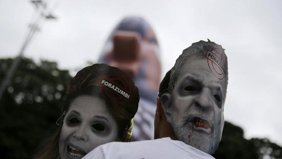 3月13日巴西各地爆发反政府示威。示威者戴着前总统卢拉和现总统罗塞夫的面具，要求罗塞夫下台。