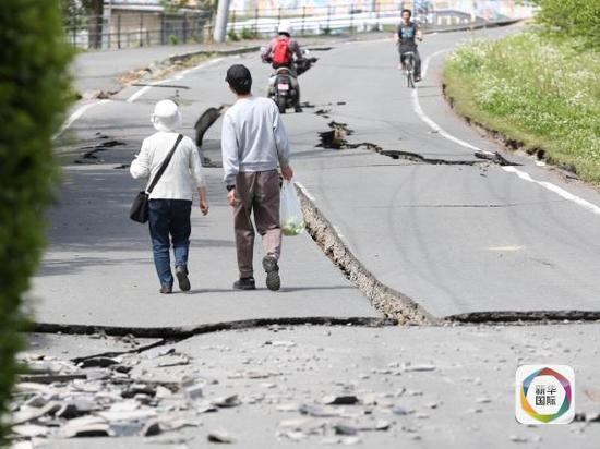 4月16日，在日本熊本县益城町，人们行走在遭地震损毁的街道上。 新华社记者 刘天 摄 