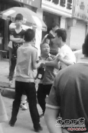 付某（右）与城管执法人员厮打在一起。目击者手机视频截图