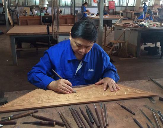 　　刘更生以及他的团队设计制造了北京APEC会议所用的皇宫椅。图为刘更生在雕刻座屏上的卷草图案。受访者供图