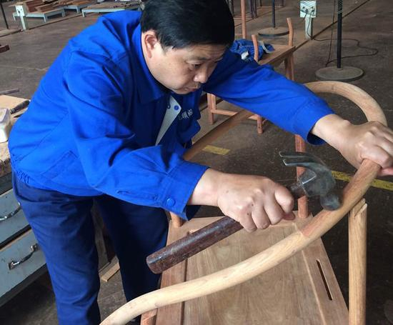 刘更生以及他的团队设计制造了北京APEC会议所用的皇宫椅。图为刘更生拿锤子凿卯。受访者供图