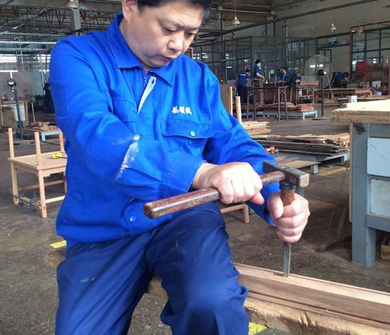 　　刘更生以及他的团队设计制造了北京APEC会议所用的皇宫椅。图为刘更生向记者示范正确的打孔坐姿和手法。受访者供图