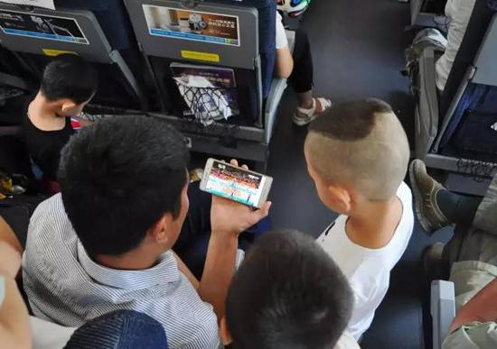 △&nbsp;在高铁列车上，乘客用手机观看里约奥运会女排决赛的视频直播。（图/视觉中国）