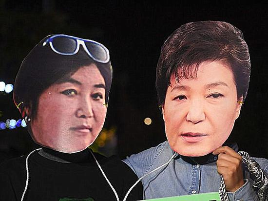 　　10月27日，首尔，抗议者戴着朴槿惠（右）和崔顺实的头像。（新华/法新）