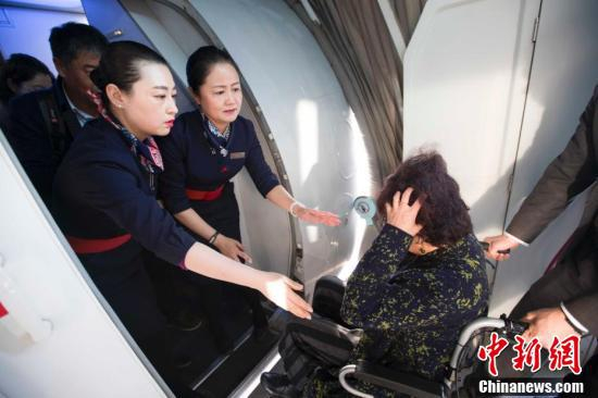 飞机落地后，魏芳（右二）帮助身体不适的乘客乘坐轮椅。