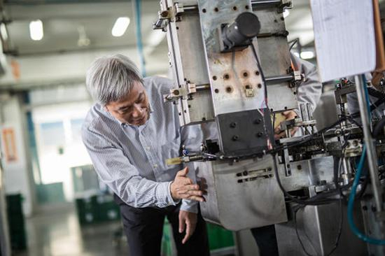  上海真彩文具股份有限公司董事长黄小喜正在调试多工位笔头加工机