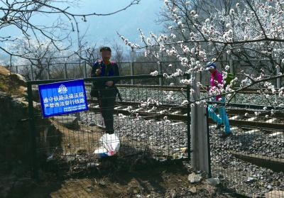 游客翻越障碍到铁路里拍摄