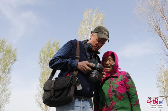 乔治•斯坦梅茨给当地农牧民看他拍摄的图片。中国网 杨佳/摄