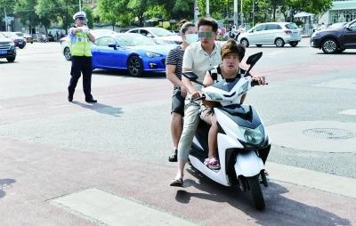 ▲东城张自忠路口，一辆电动车违规载人被交警拦停摄/记者郭谦