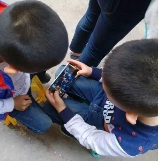 ▲小学生聚在一起玩手机游戏。&nbsp;图片来自网络