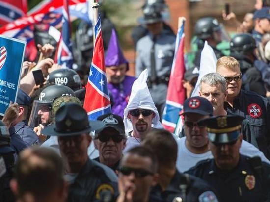 7月8日，夏洛茨维尔，保护“南方邦联”纪念雕塑集会现场，三K党成员（中）和其他白人种族主义者隔着警察与反对集会的抗议者对峙。（新华/法新）