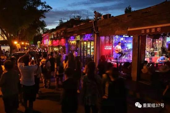 ▲8月24日晚间，后海银锭桥附近某酒吧，一名歌手正在演出，街上游客川流不息。 &nbsp;新京报记者彭子阳 &nbsp;摄