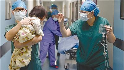 福建省妇幼保健院小儿外科有13名医生，一天最多要做16台手术，医生平均每天工作时间超10个小时。该院前段时间成功为一名患肾母细胞瘤的2岁女童完成肿瘤切除手术。图为该院小儿外科医生黄文华（左）和手术室护士郑伟熙在手术前安抚女童。新华社记者 宋为伟摄