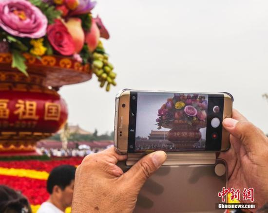 民众在北京天安门广场国庆主题花篮前拍照（资料图）。中新社记者&nbsp;贾天勇摄