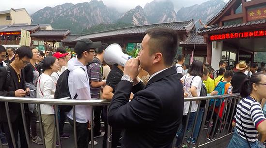  张仕庆拿起喇叭走向游客排队区。澎湃新闻记者 胡芮默 图