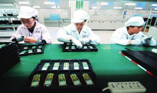 2010年11月，江西省九江市共青城工业园区，赛龙通信公司的工作人员在进行手机芯片生产作业。图/视觉中国