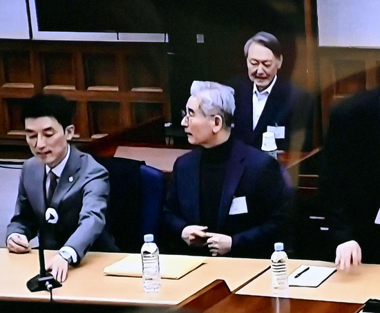 ▲当地时间2026年2月19日，韩国首尔的电视屏幕显示韩国前总统尹锡悦（后排）在首尔中央地方法院的叛乱案宣判庭审中 图据视觉中国